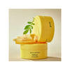 Yellow container of Green Tangerine Vita-C eye gel patches with a leaf on a beige background