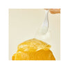 Close-up of a spoon with a scoop of yellow dessert on a beige background